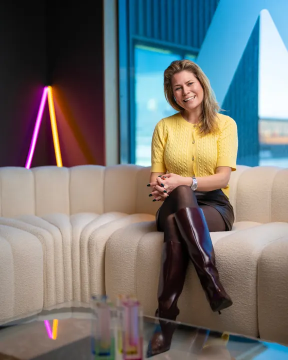 An Adway team member smiling on a cream sofa in the Gothenburg office
