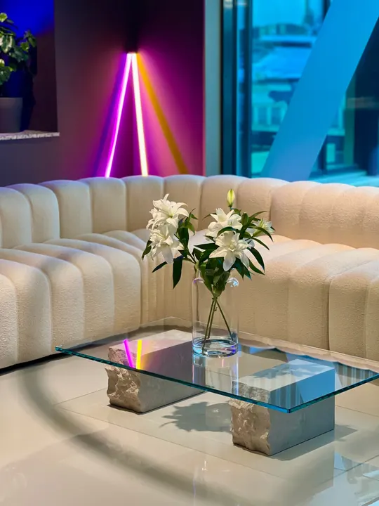 A cream sofa and glass table with white lilies in the Adway office